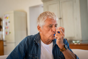 Older man using inhaler for asthma