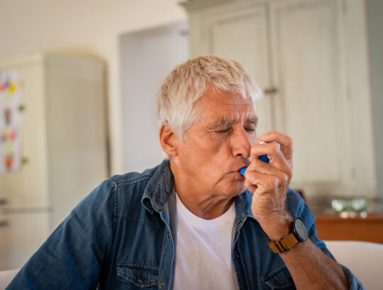 Older man using inhaler for asthma